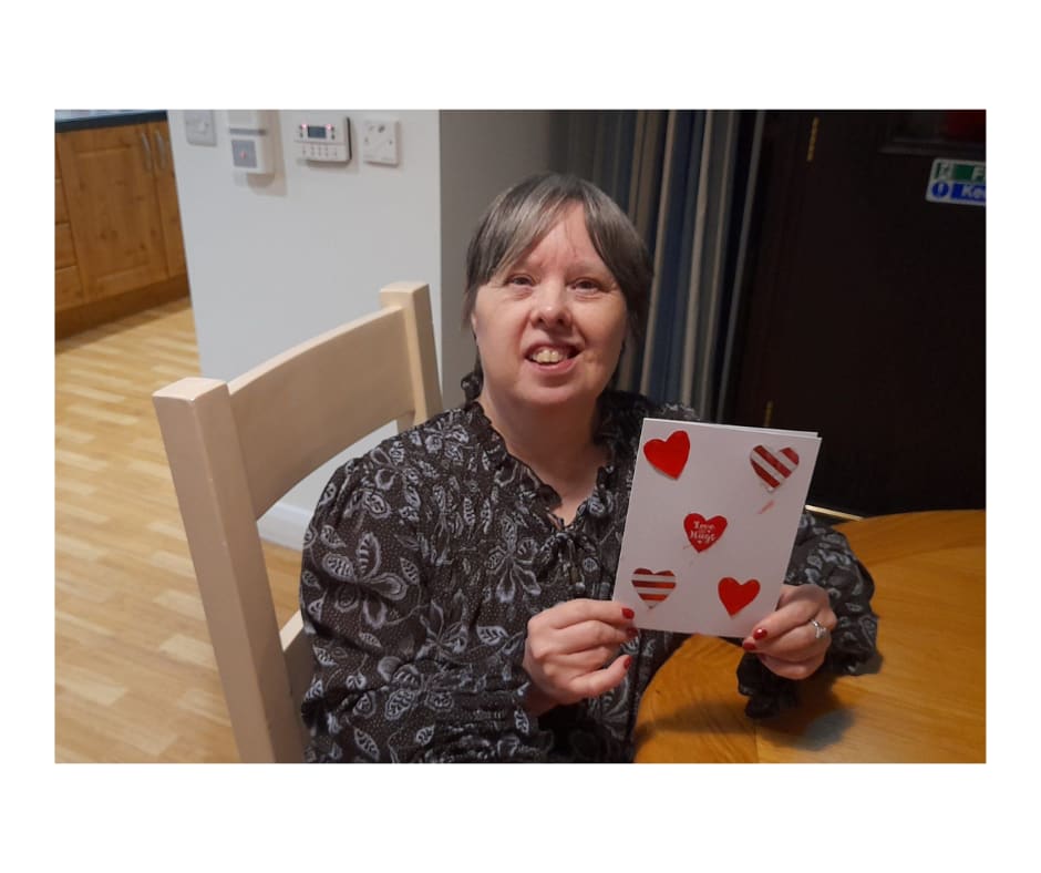 Woman sitting at table holding a valentine card.
